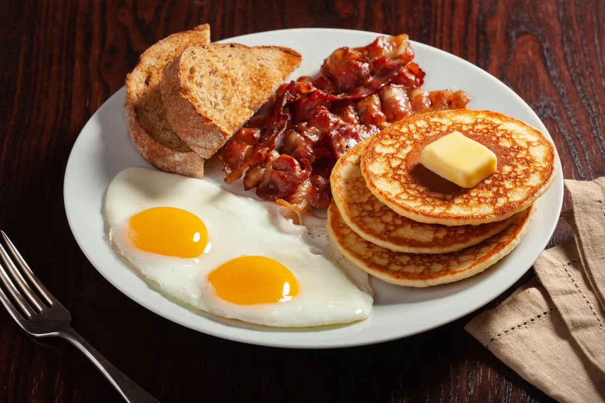 Großes Frühstück mit Eiern, Speck und Pancakes